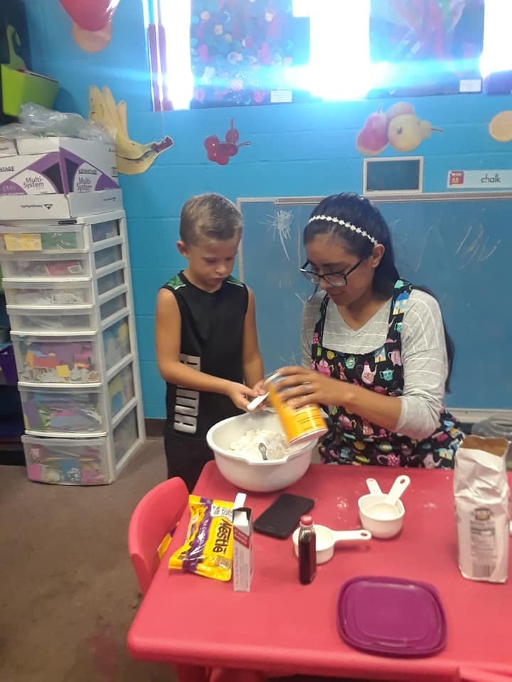 Teen and child mixing ingredients in a bowl on a red table