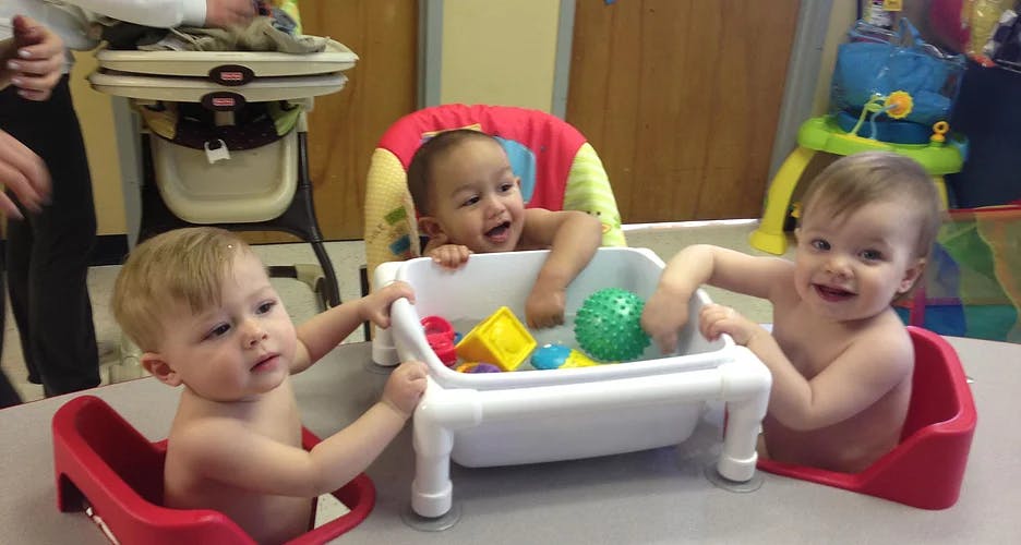 Three babies playing with toys in a classroom