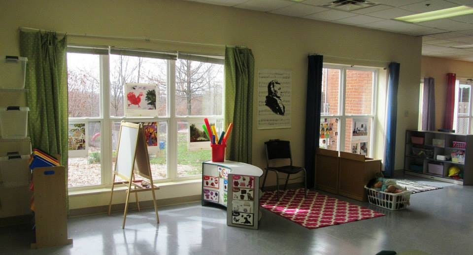 Classroom with large windows, easel, and red rug