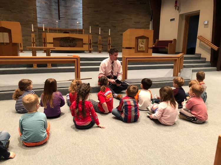 Person reading to a group of children sitting on the floor