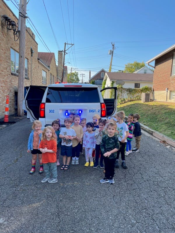 Group of children standing in front of a white vehicle with its back doors open