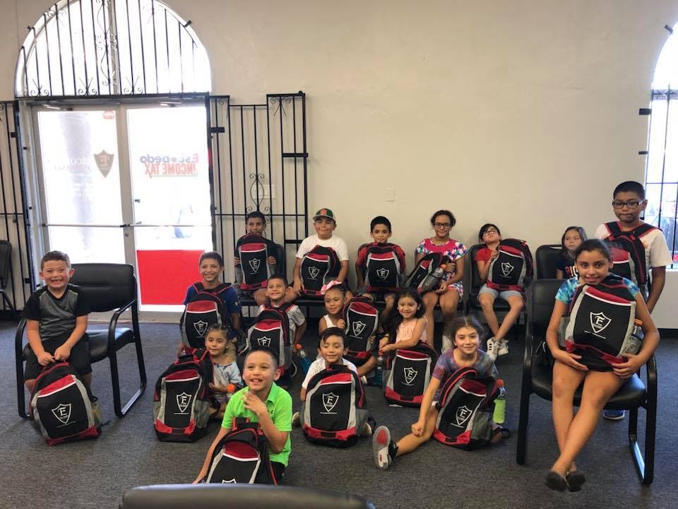 Group of children and teens posing with backpacks
