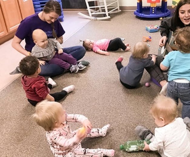 Two people with multiple children playing on the floor