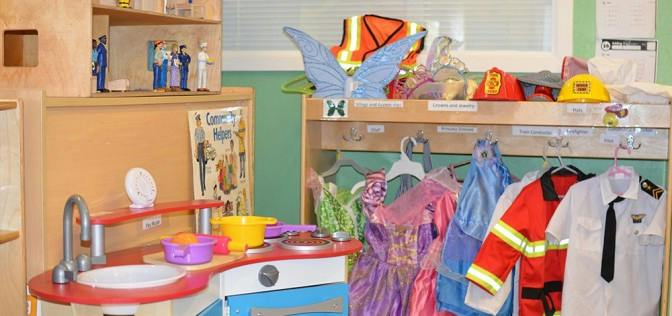 Play kitchen with dress-up clothes including a firefighter jacket and pilot shirt