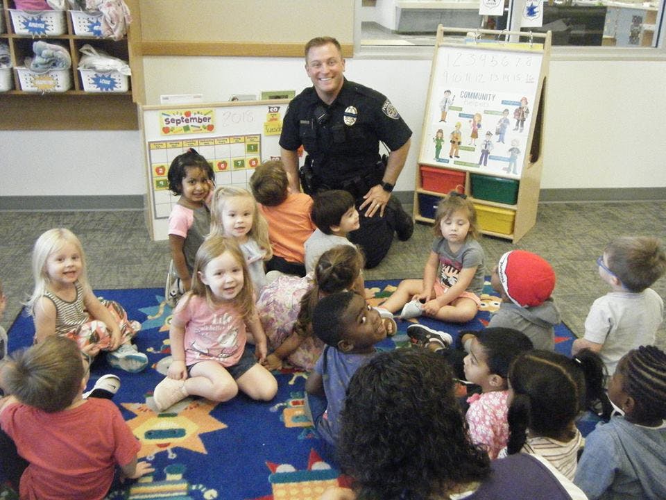 Police officer kneeling with a group of children in a classroom