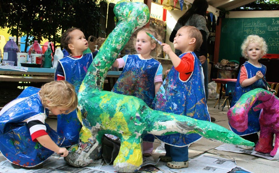 Children painting a large dinosaur sculpture
