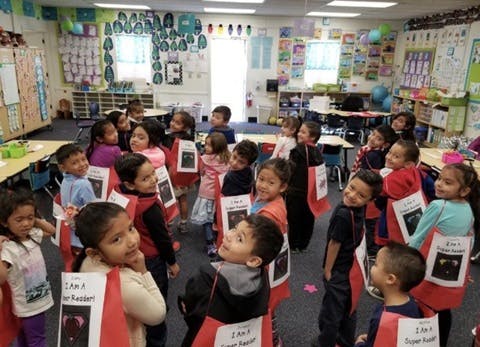 Children in red and black aprons in a classroom