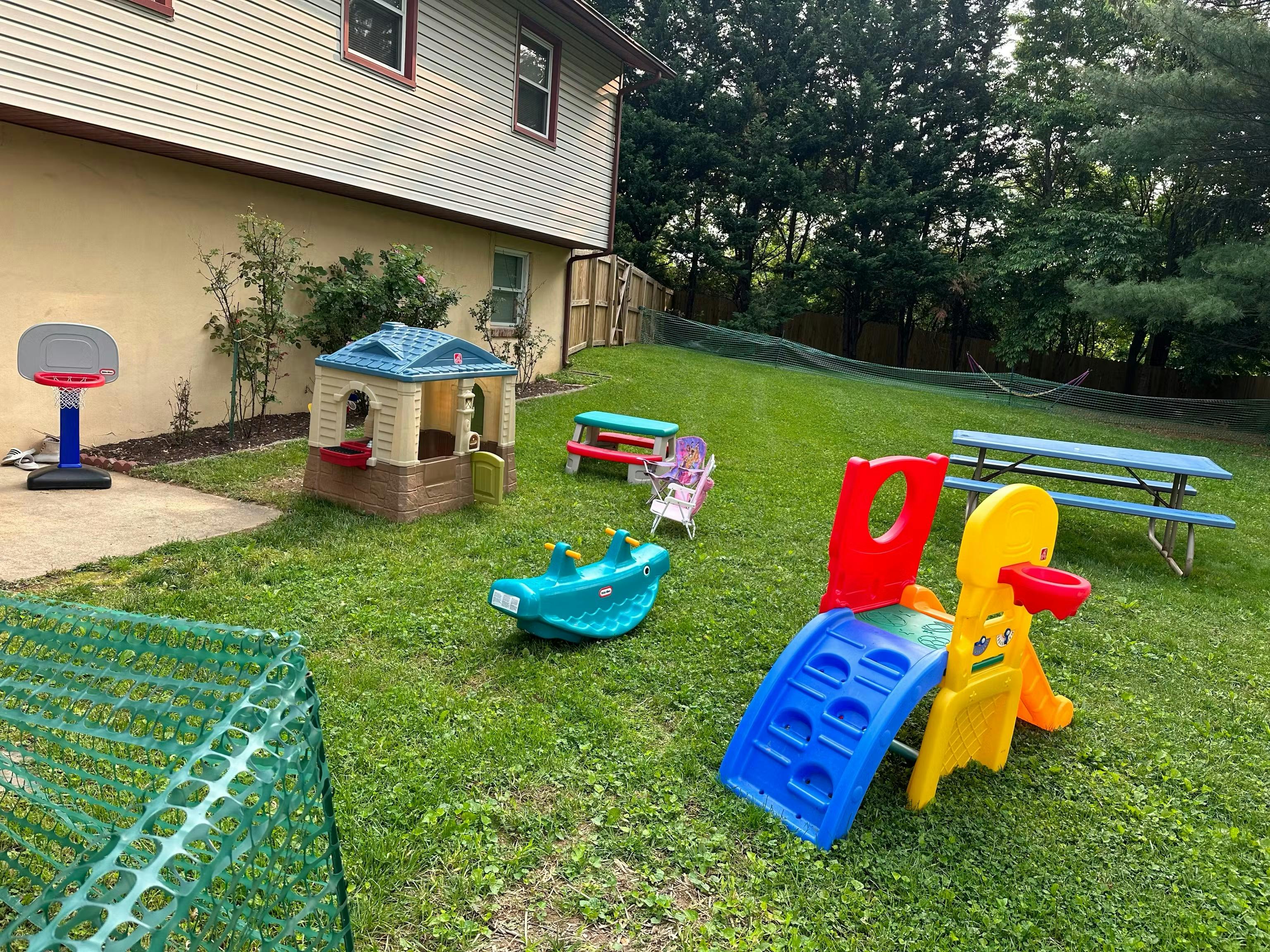 Plastic playground equipment and tables in a residential backyard