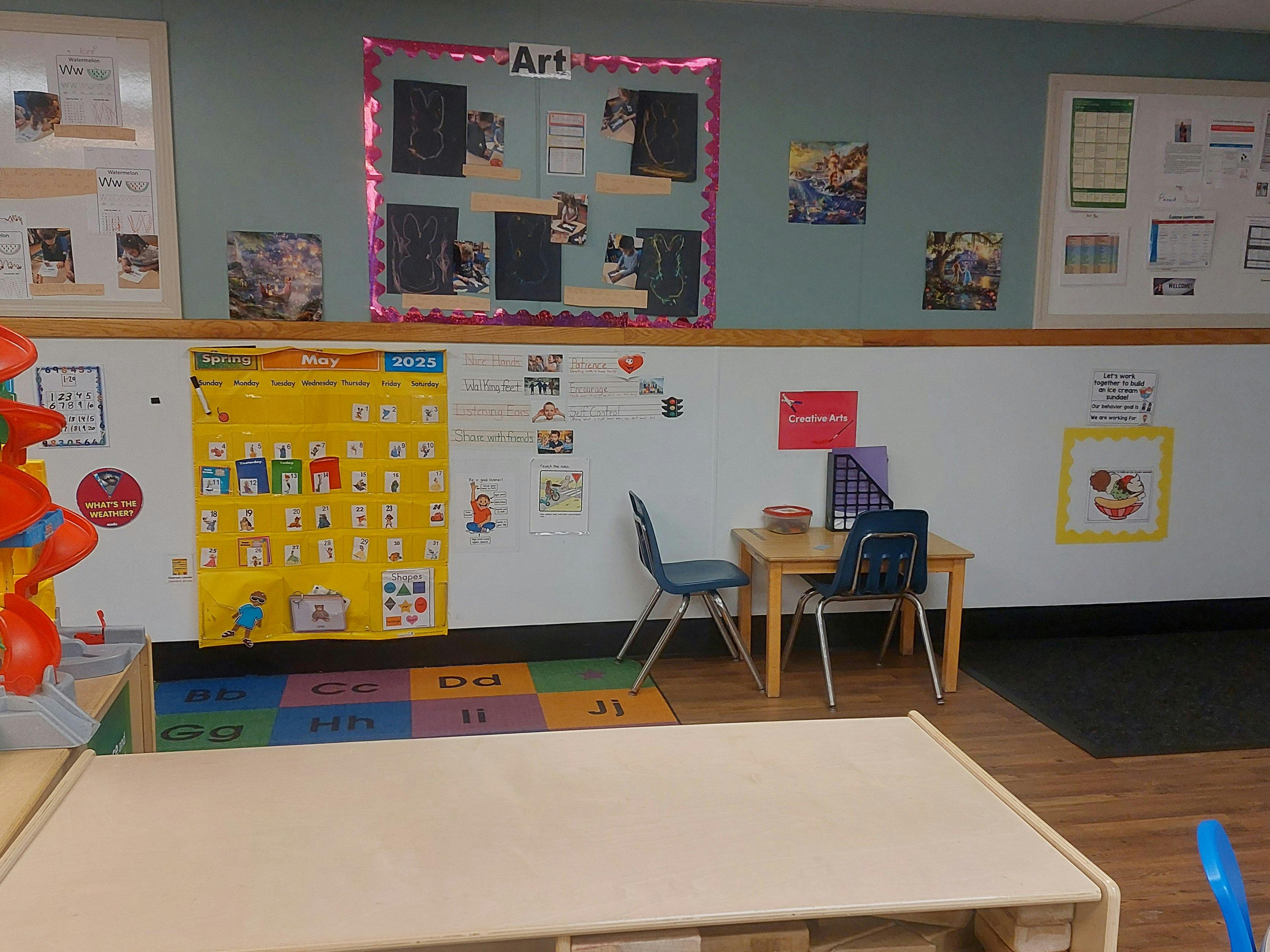 Classroom with children's artwork, an alphabet rug, and a monthly calendar