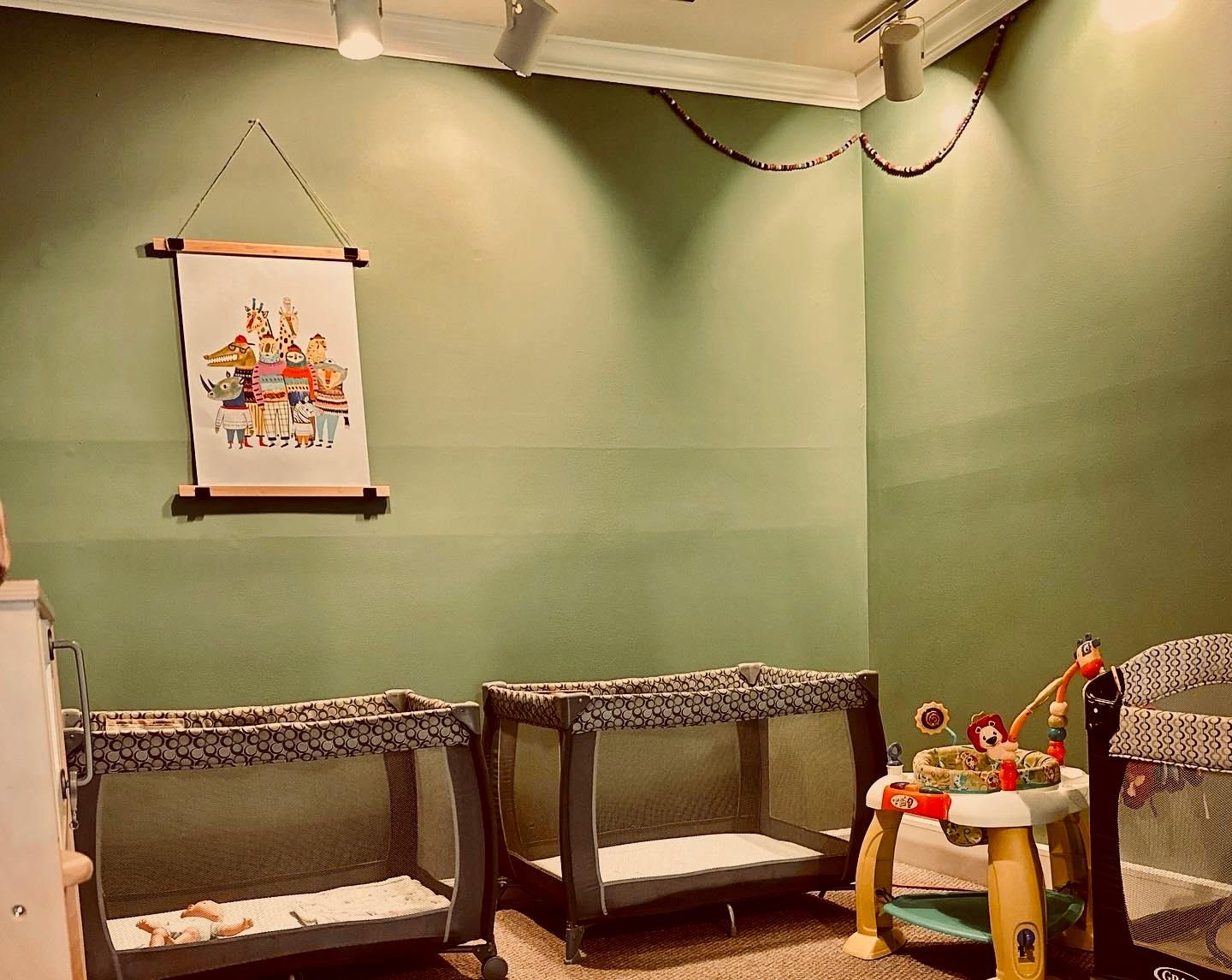 Two portable cribs and a baby activity center in a room