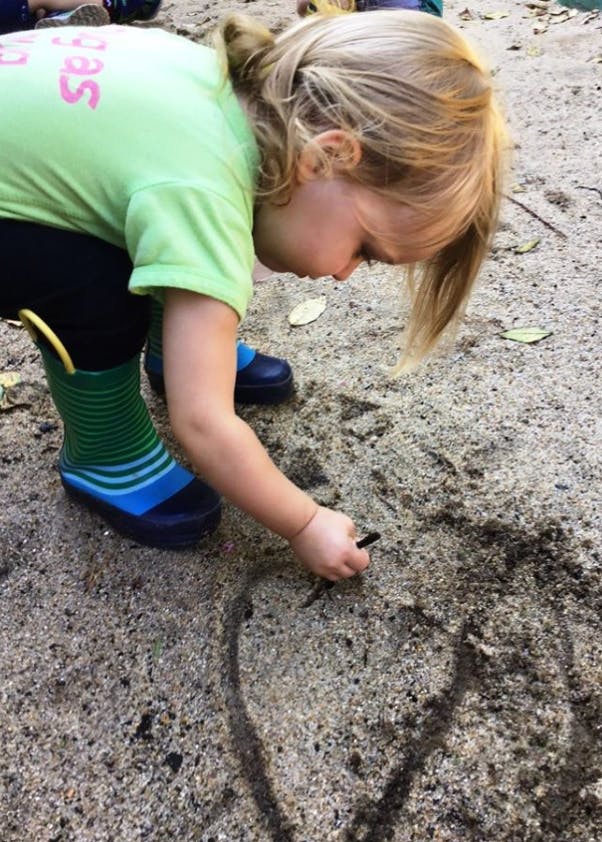Child drawing in sand with a stick