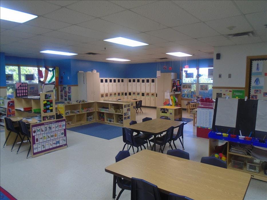 Empty classroom with tables, chairs, storage cubbies, and an alphabet chart