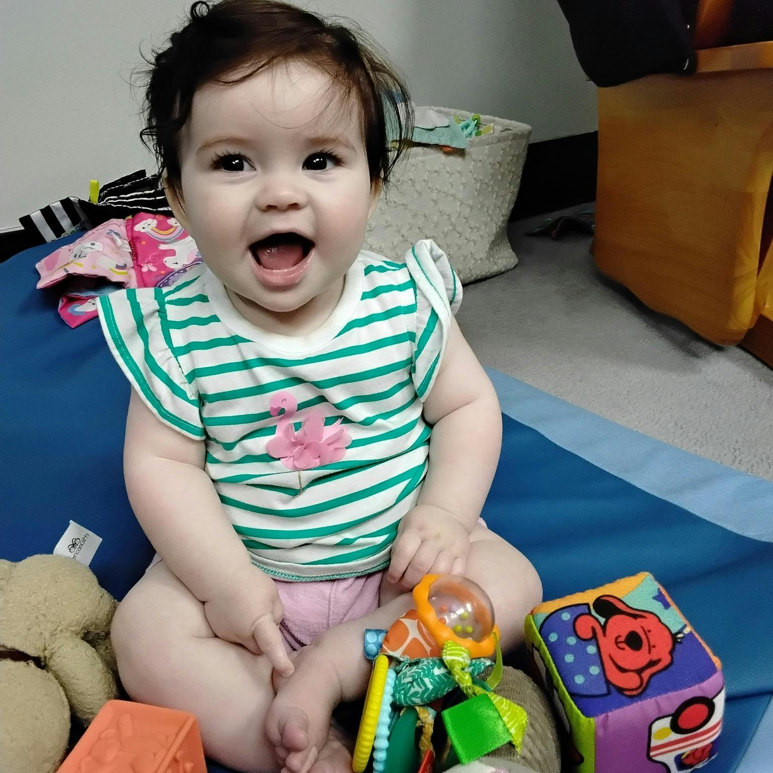 Child sitting on a blue mat with toys