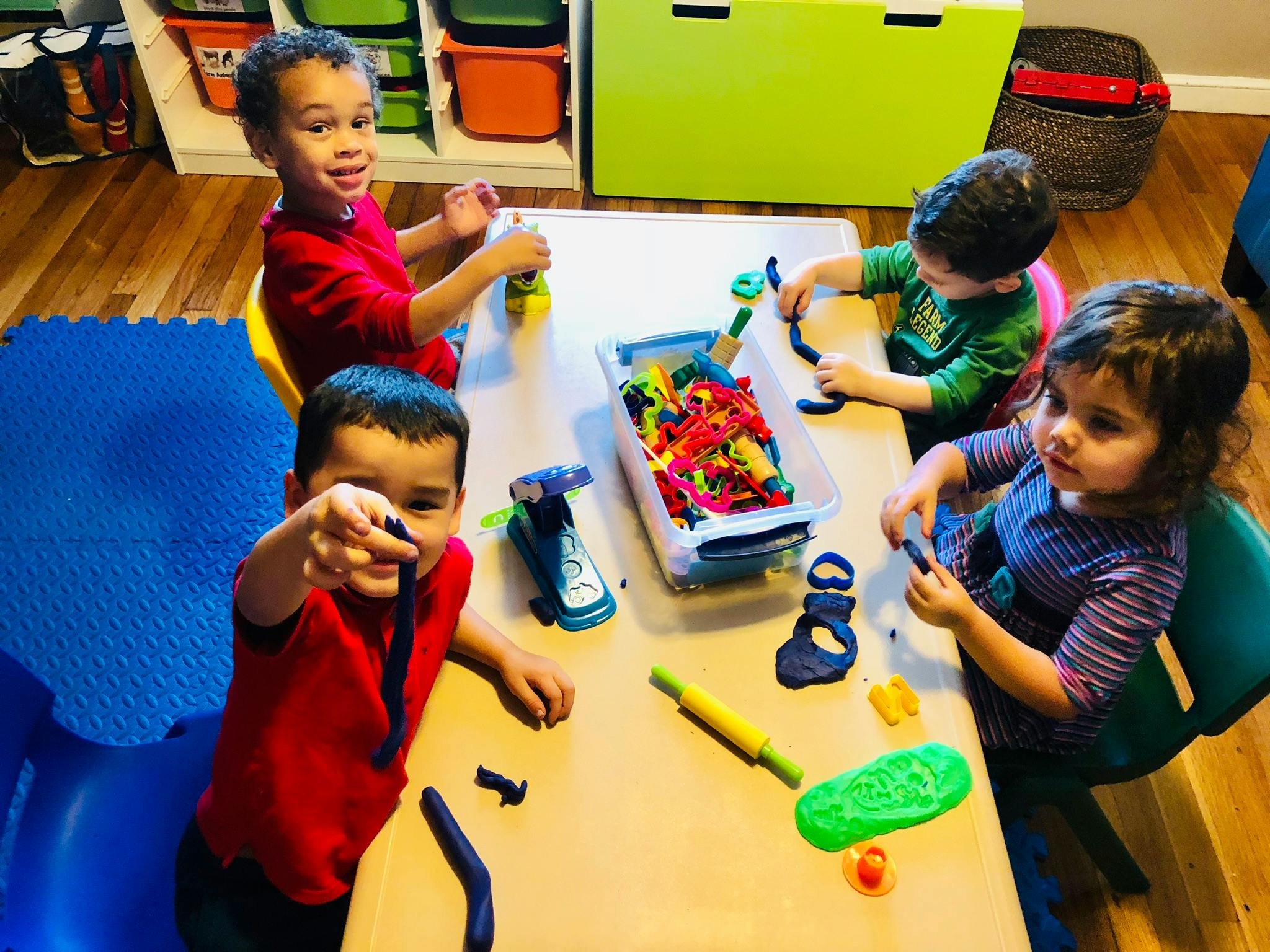 Four children playing with modeling clay at a table