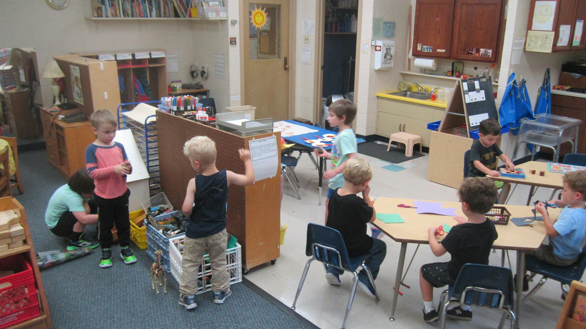 Children playing and working at tables in a classroom