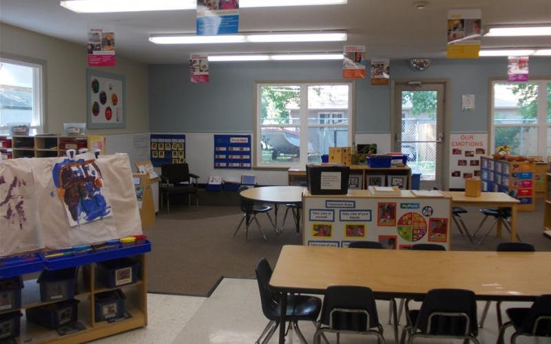 An empty early childhood classroom with small tables and chairs
