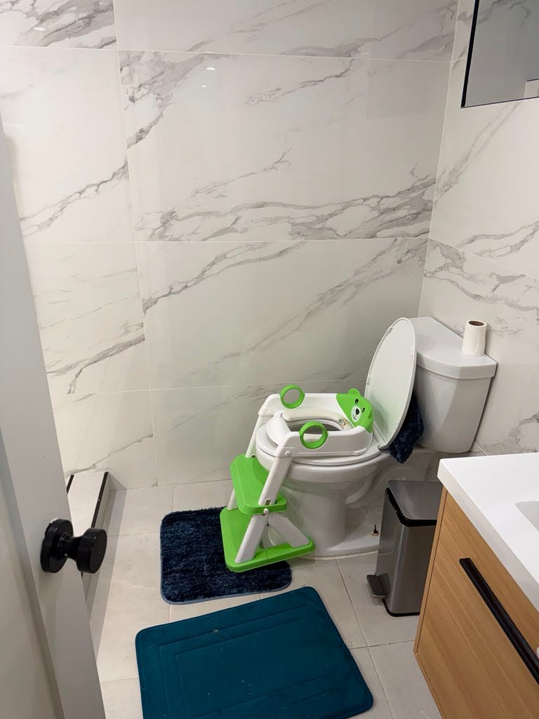 Child toilet training seat with steps attached to a toilet in a bathroom