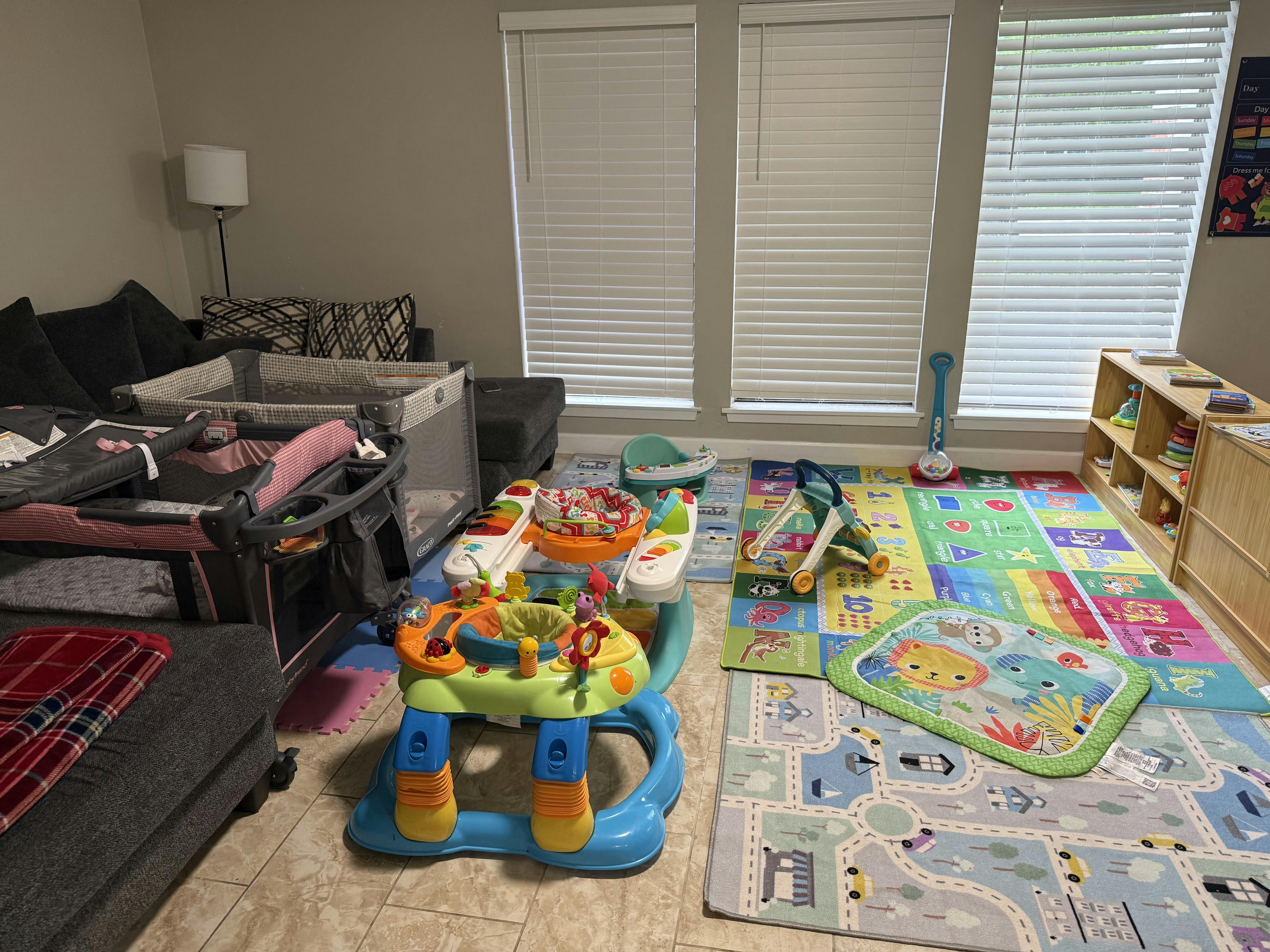 baby play area with a colorful alphabet rug, bouncer, and bassinet