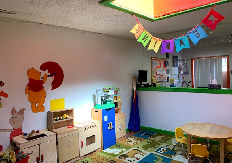 Playroom with toy kitchen, colorful rug, and banner
