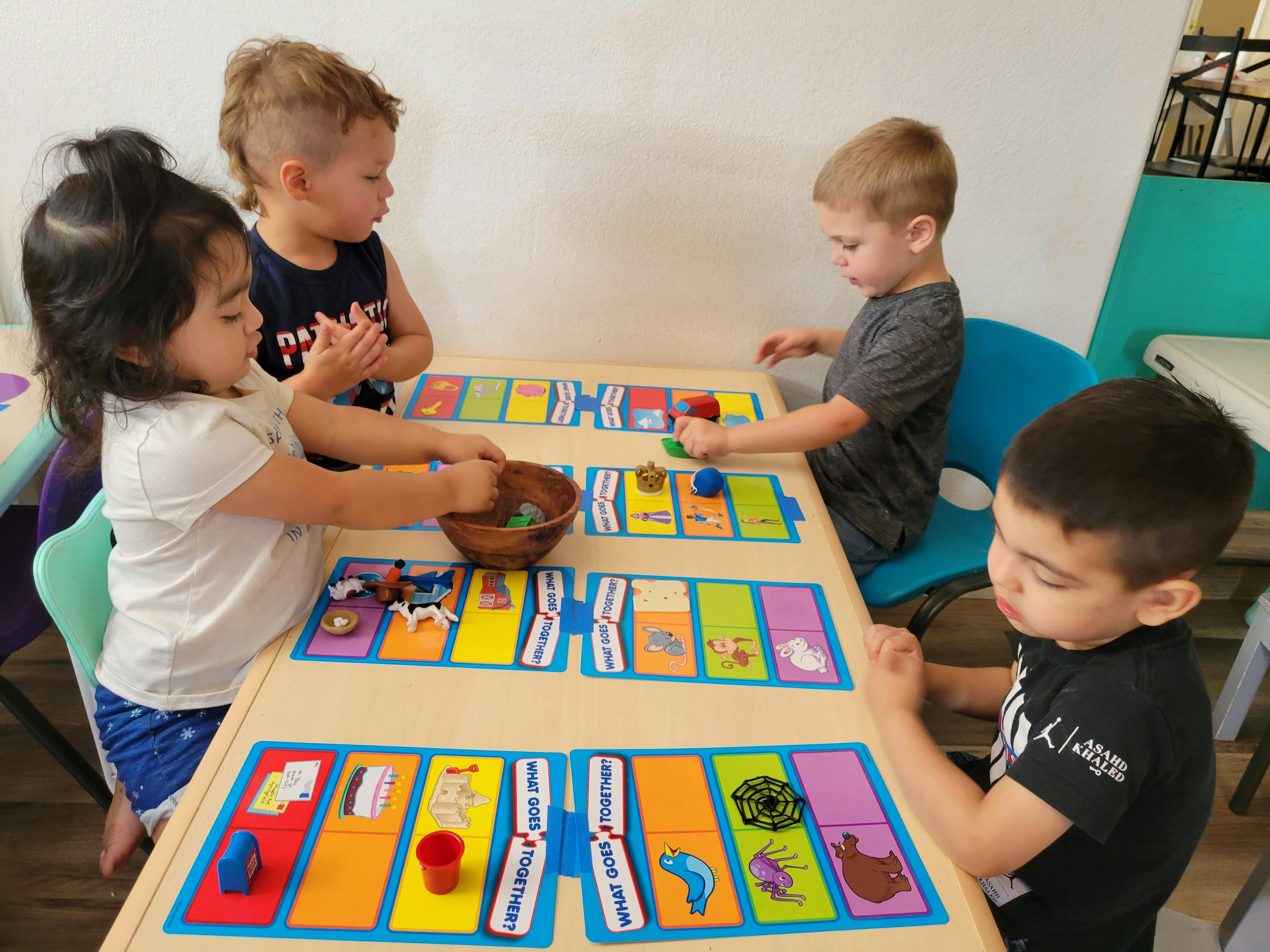 Four children playing with colorful learning games at a table