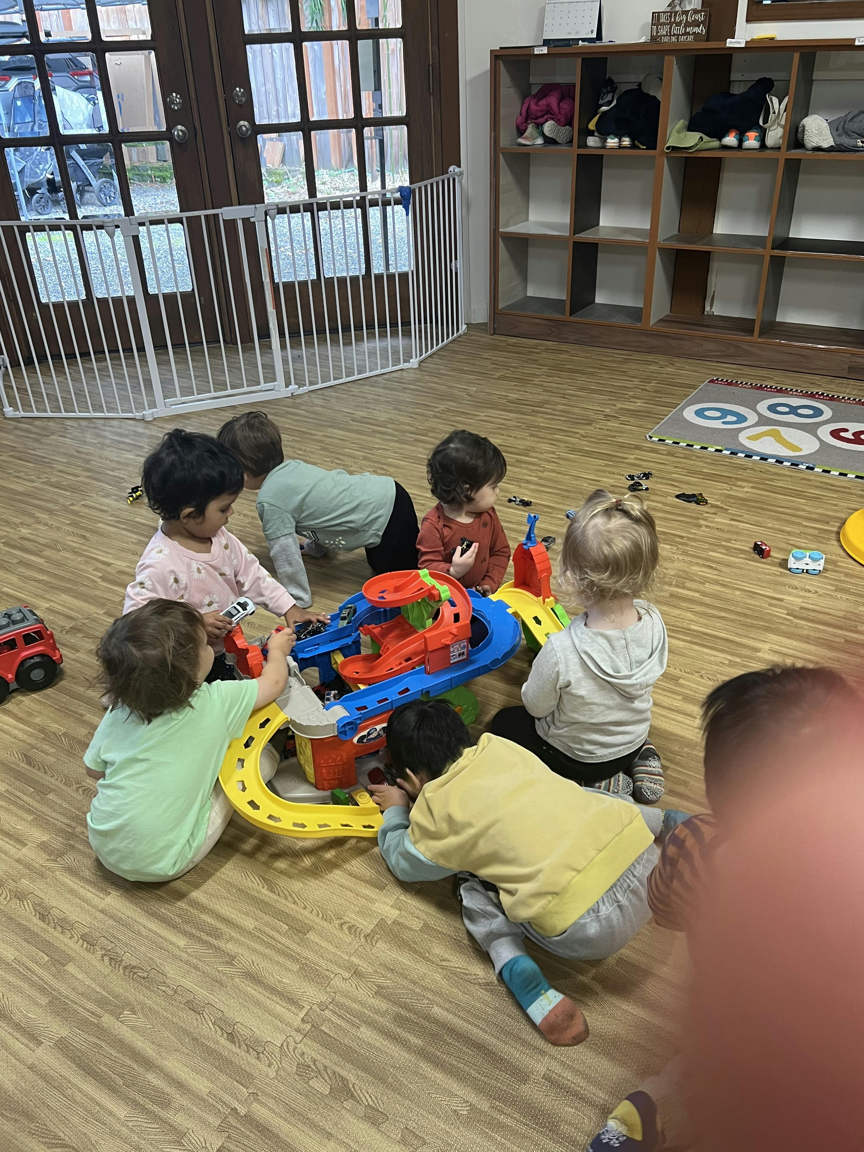 Children playing with a toy car track on the floor