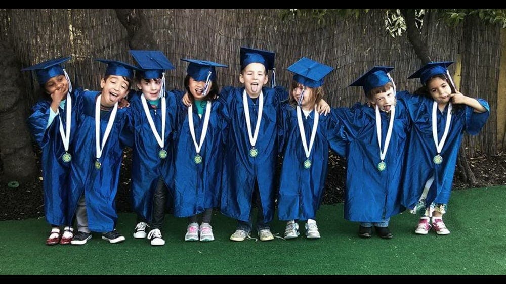 Children in graduation caps and gowns with medals