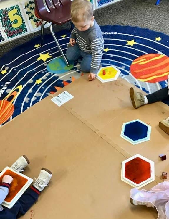 Child playing with colorful shapes on a solar system rug