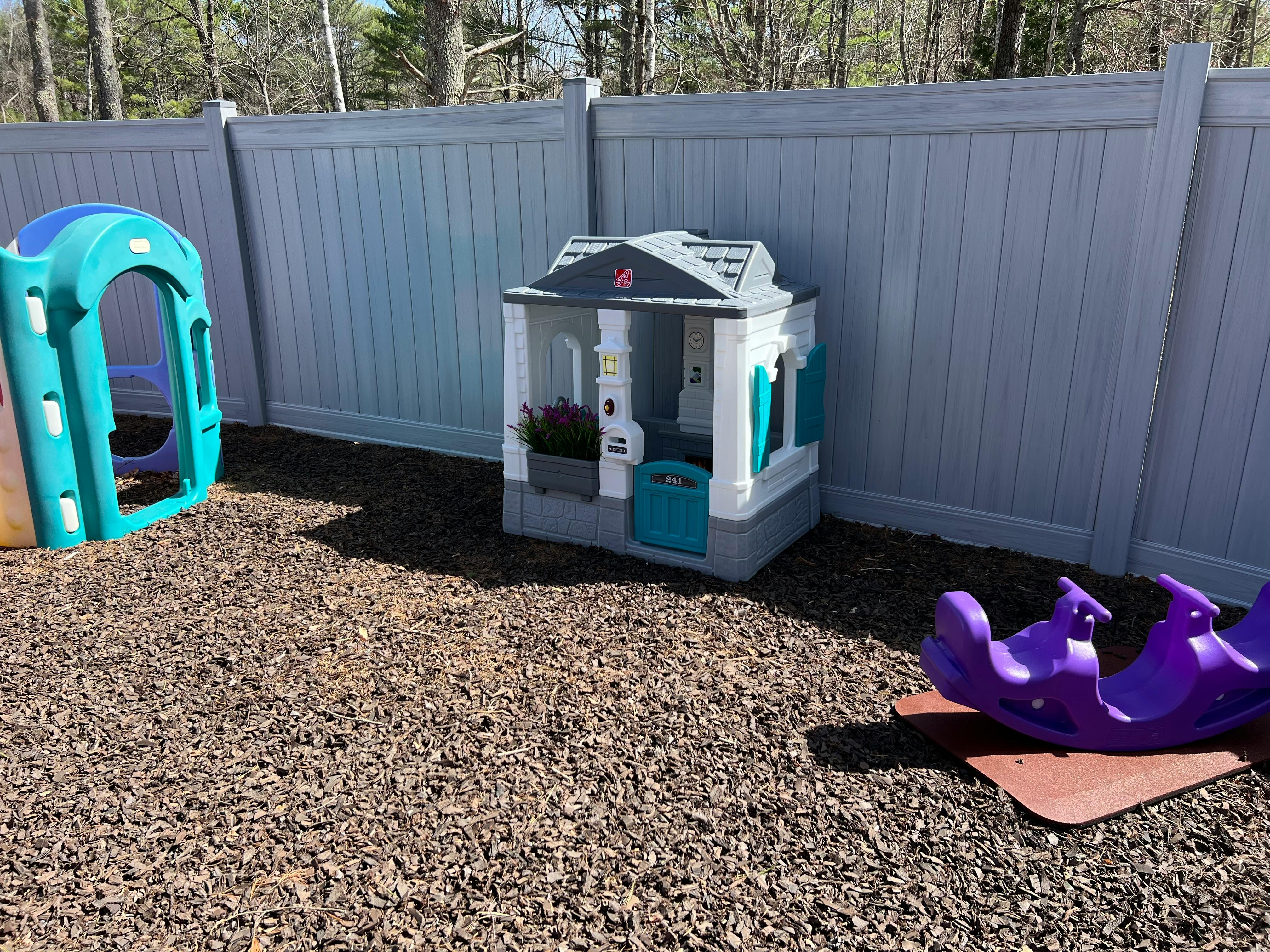 Playhouse and slide in a fenced yard