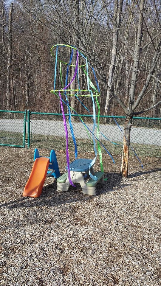 Playground with a small slide and a picnic table decorated with colorful ribbons