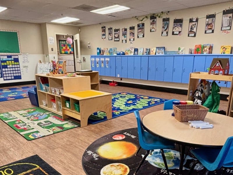 Colorful classroom with various play areas, blue lockers, and rugs