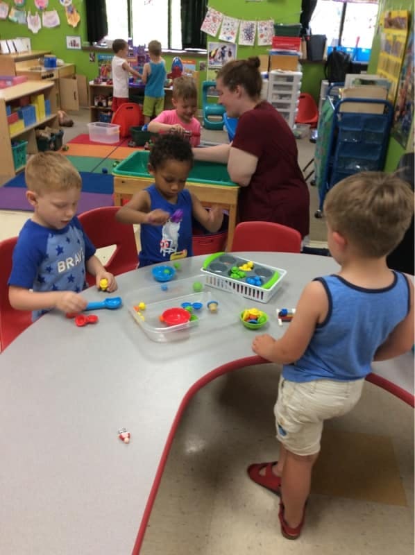Children playing with toys at a table in a classroom