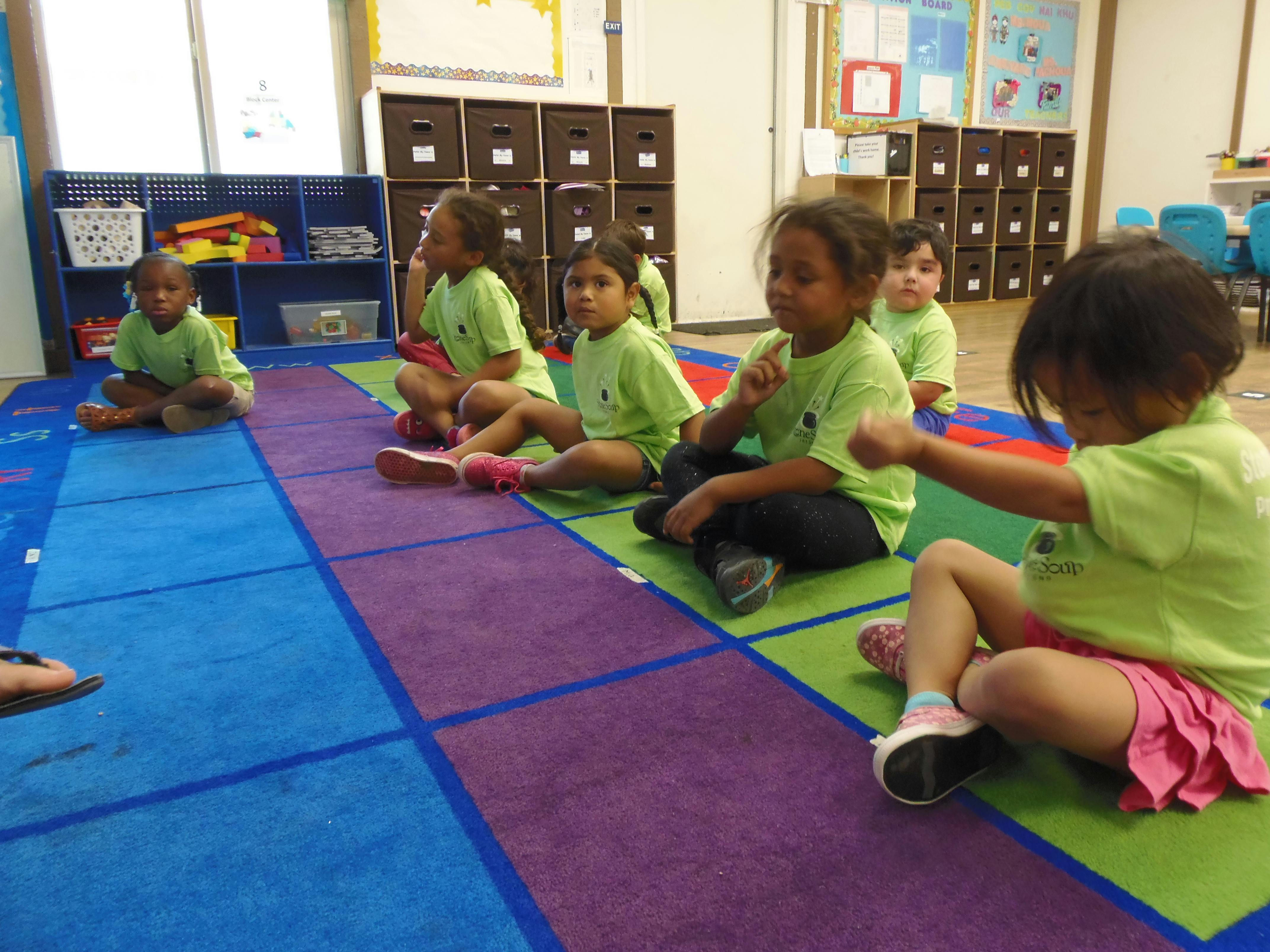 Children sitting on a colorful rug in a classroom