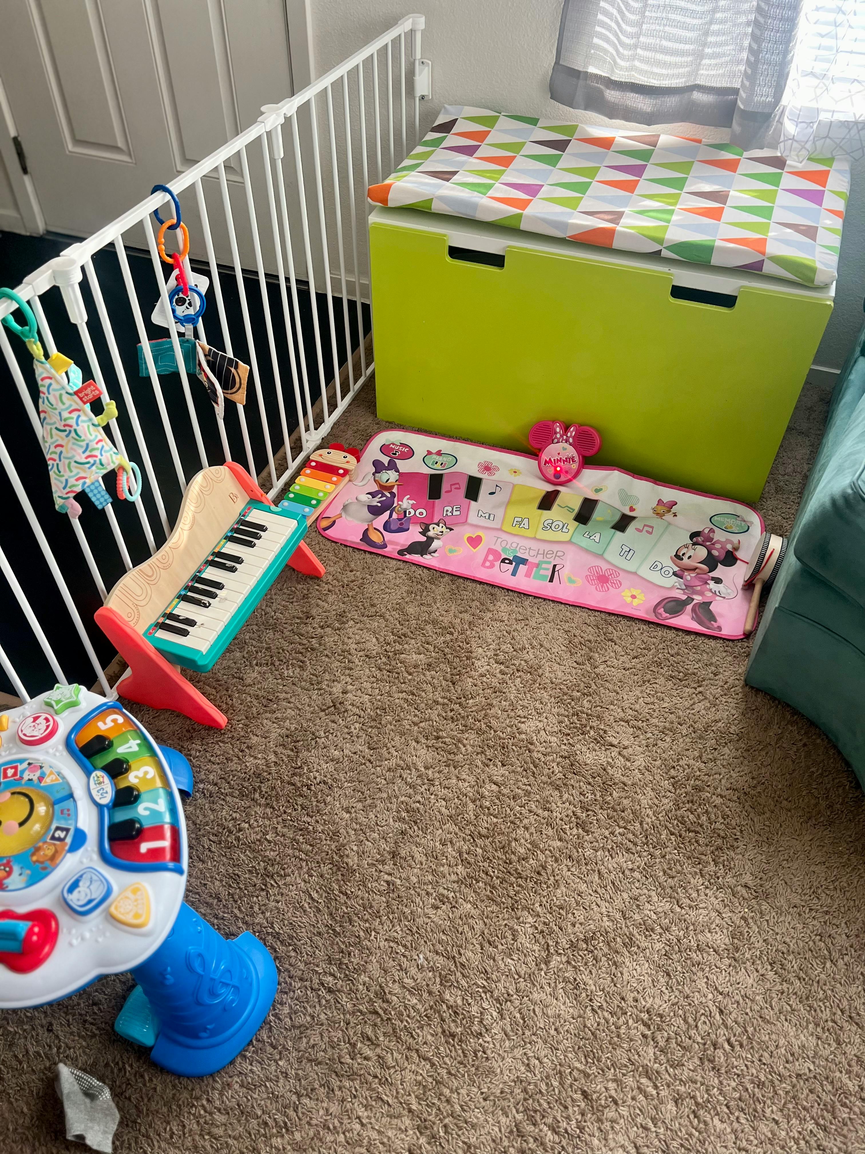 Baby gate, toy piano, and play mat on carpet