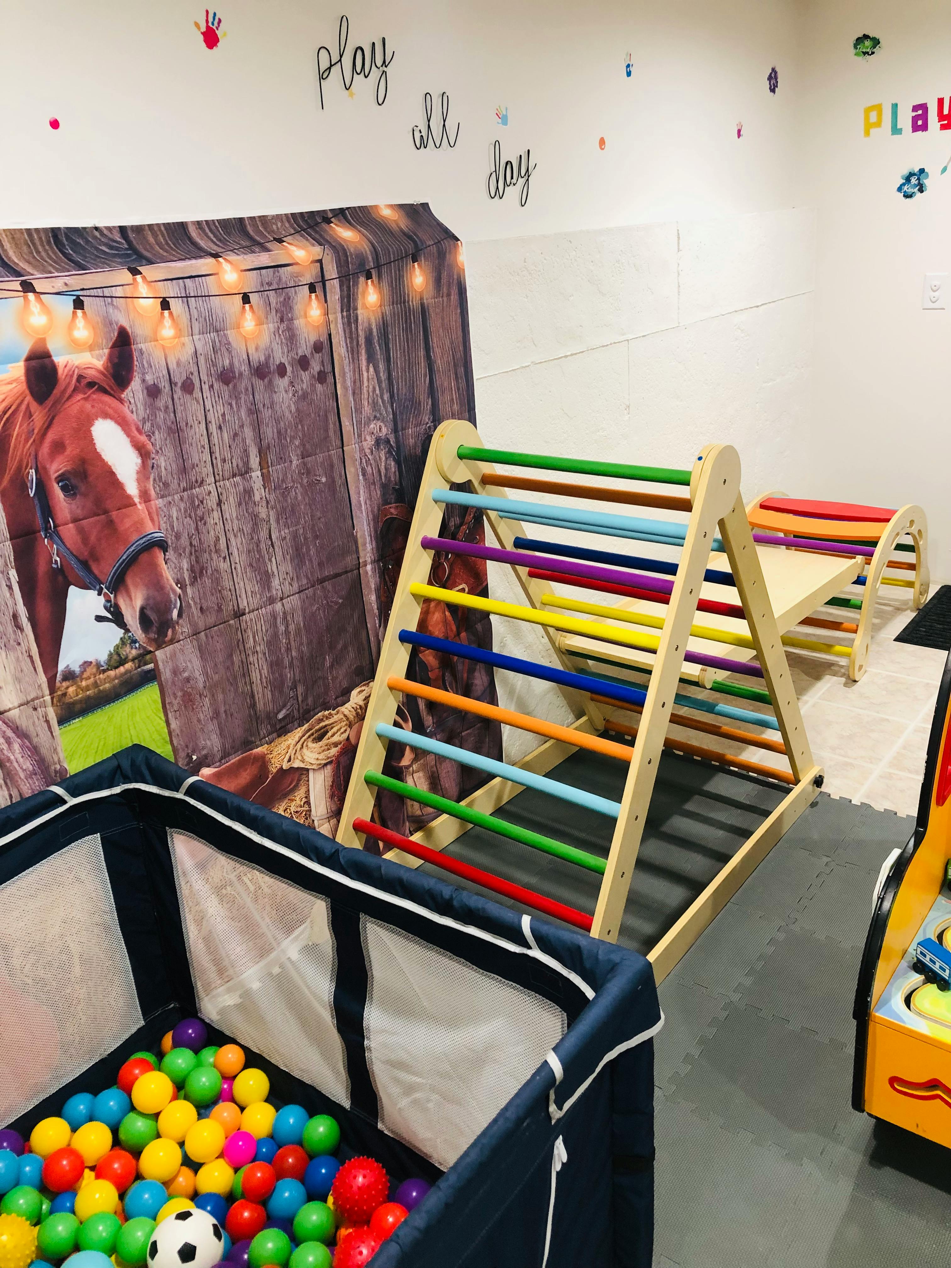 Indoor play area with a ball pit and a wooden climbing structure