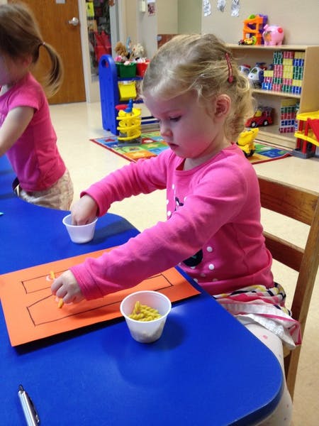 Child doing an art project at a table in a classroom