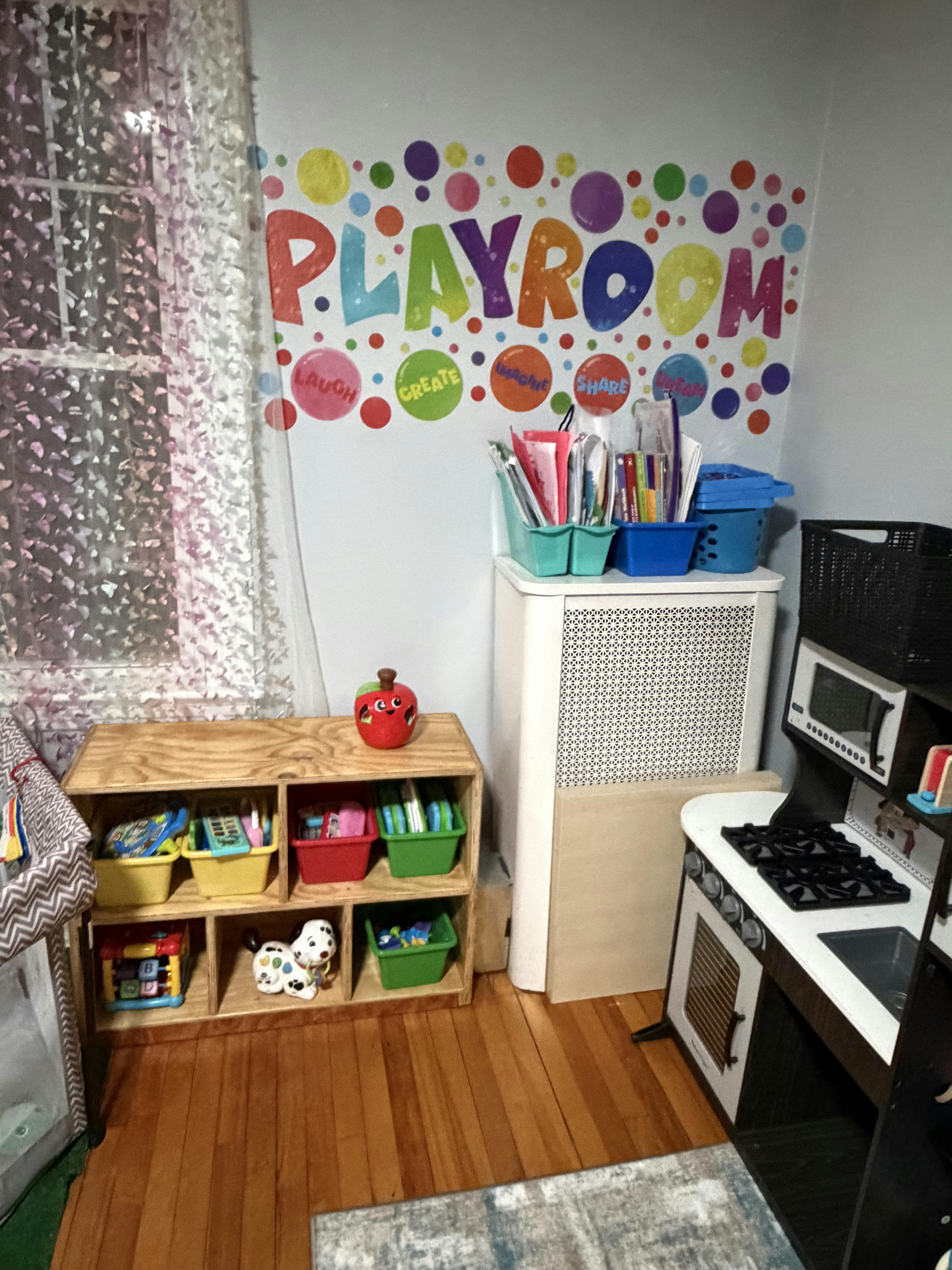 Child's playroom with cubby shelves, toy kitchen, and a "PLAYROOM" wall decal