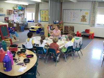 Adult reading a book to children in a classroom