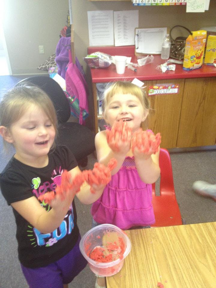 Two children playing with red playdough