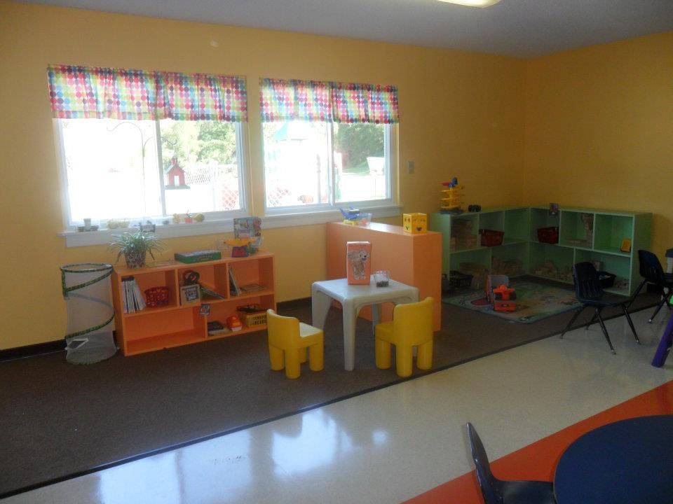 Empty classroom with small table and chairs, shelves, and windows