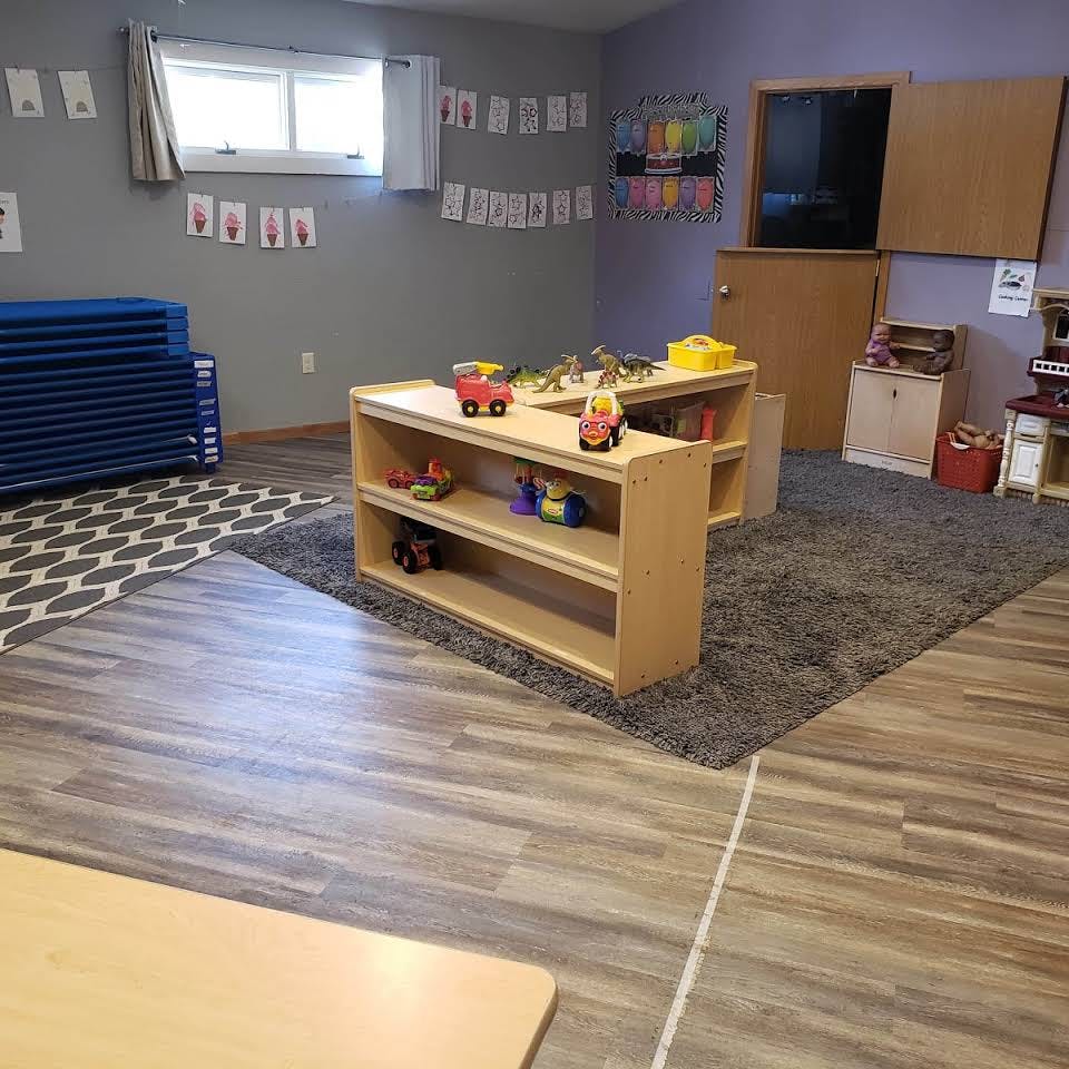 Playroom with shelves of toys, blue mats, and a rug