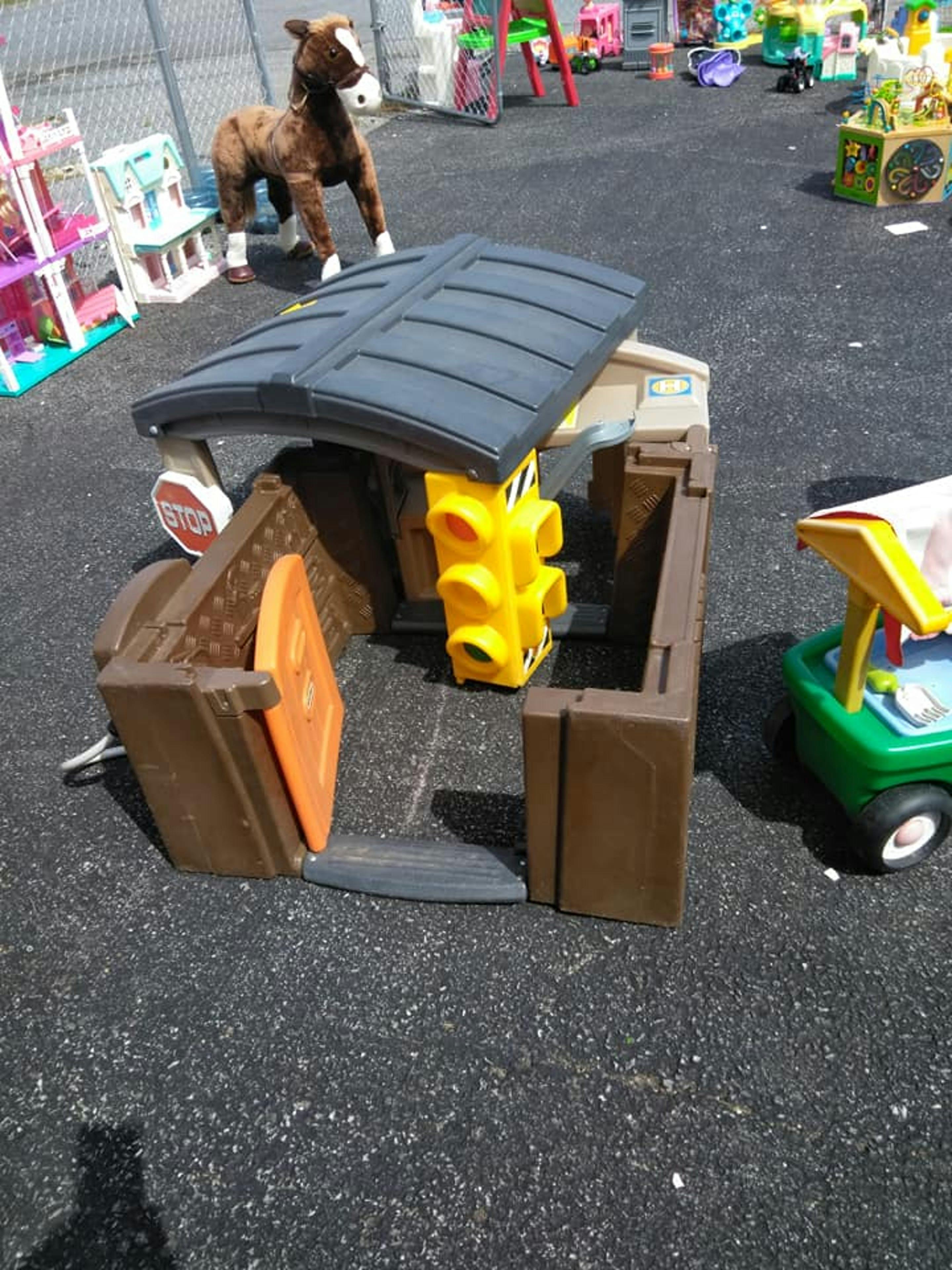 Toy playhouse with a yellow traffic light and a stuffed horse in the background