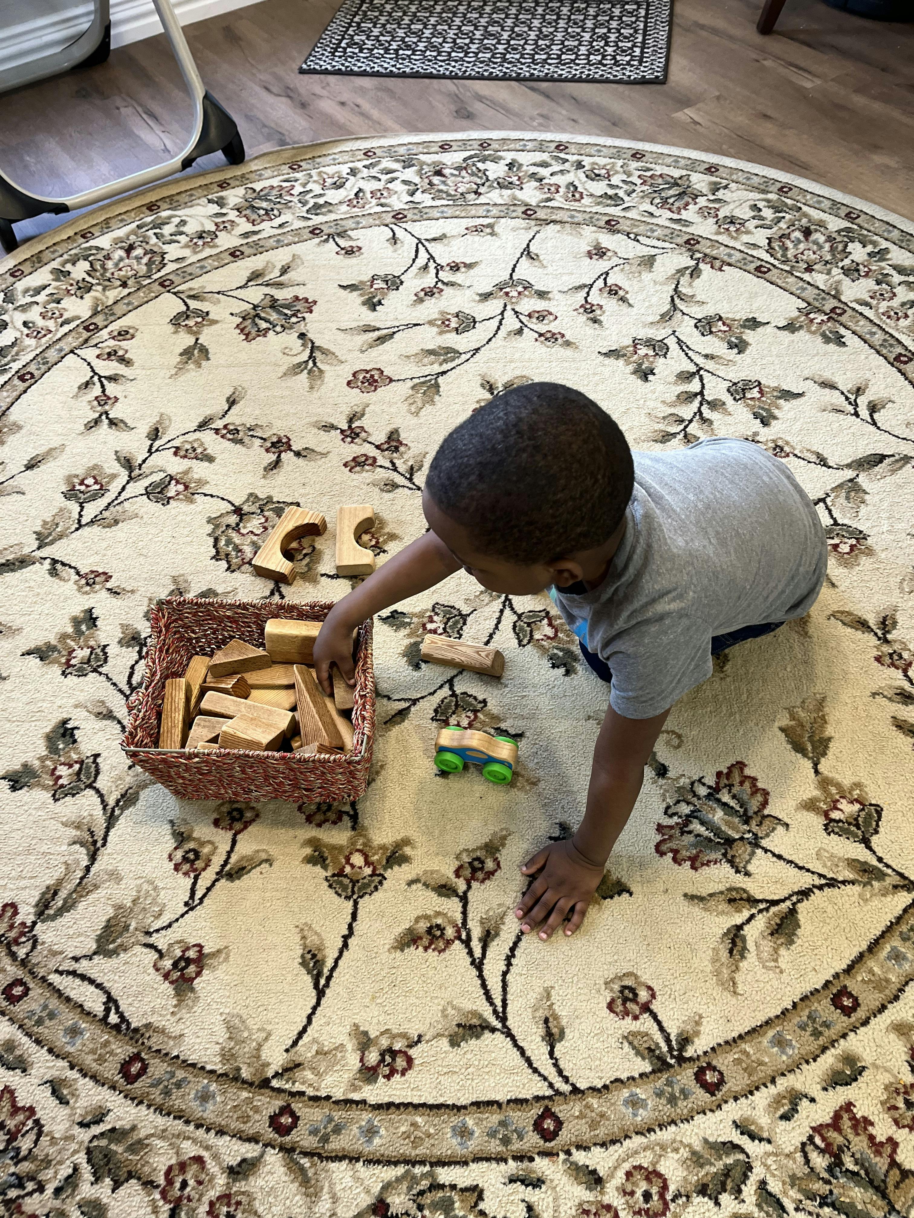 Child playing with wooden blocks on a rug