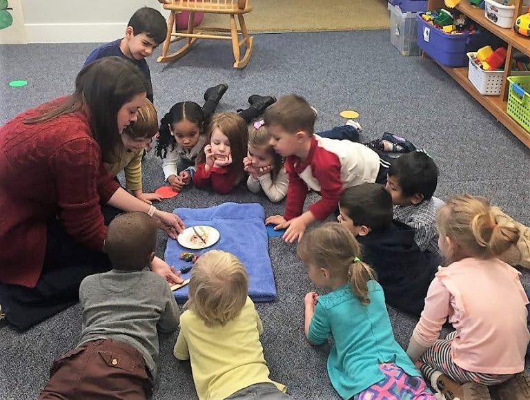Adult and children gathered on floor looking at items on a blue cloth