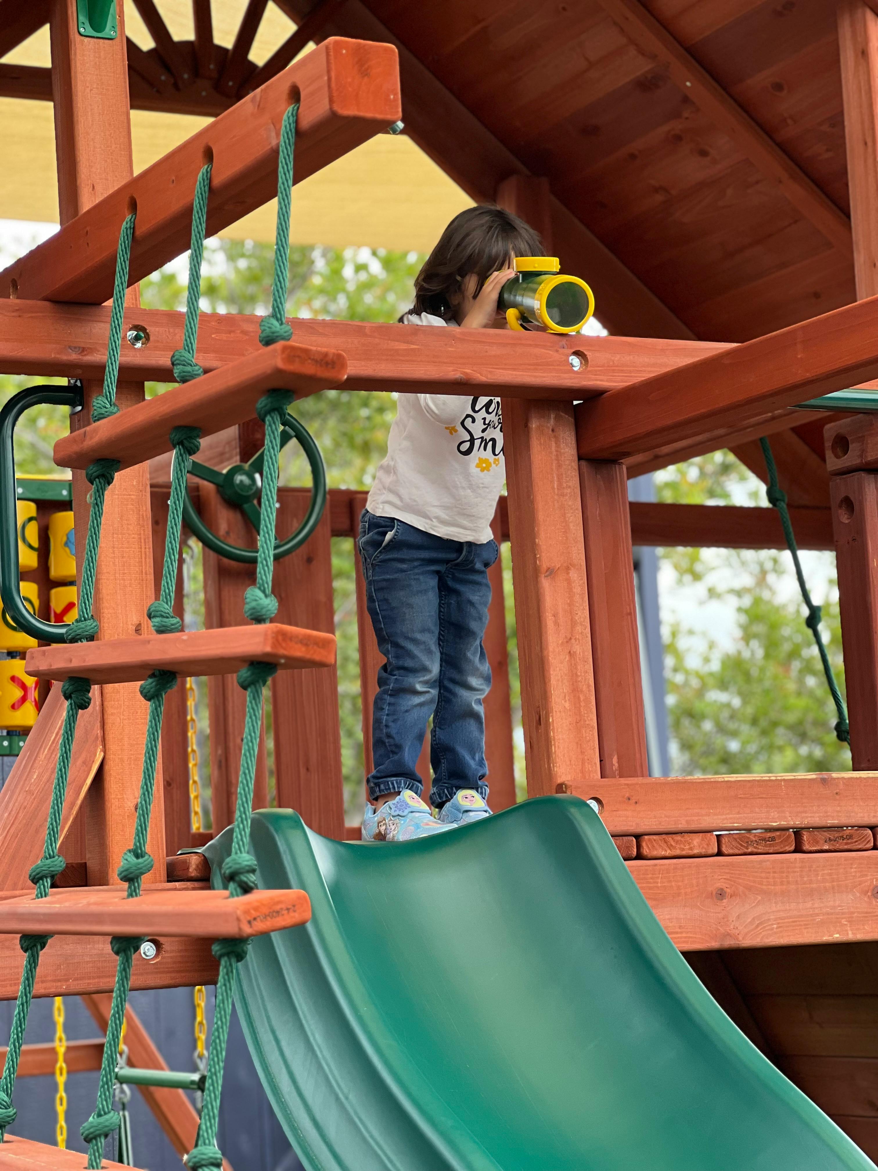 Child looking through a toy telescope on a playground structure