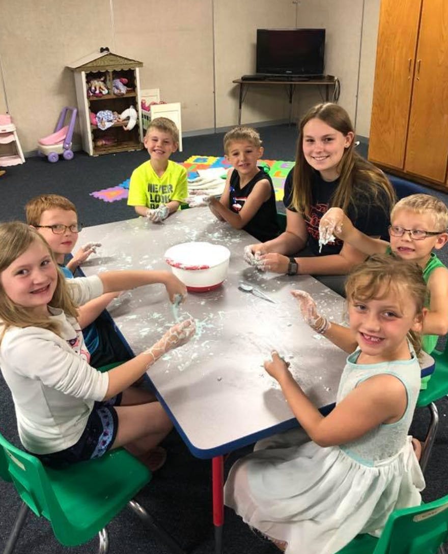 Children and a teen making crafts at a table
