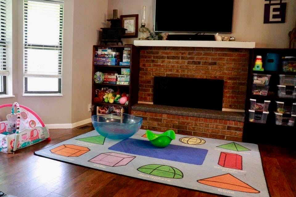 Playroom with a rug featuring geometric shapes, a baby play mat, and shelves