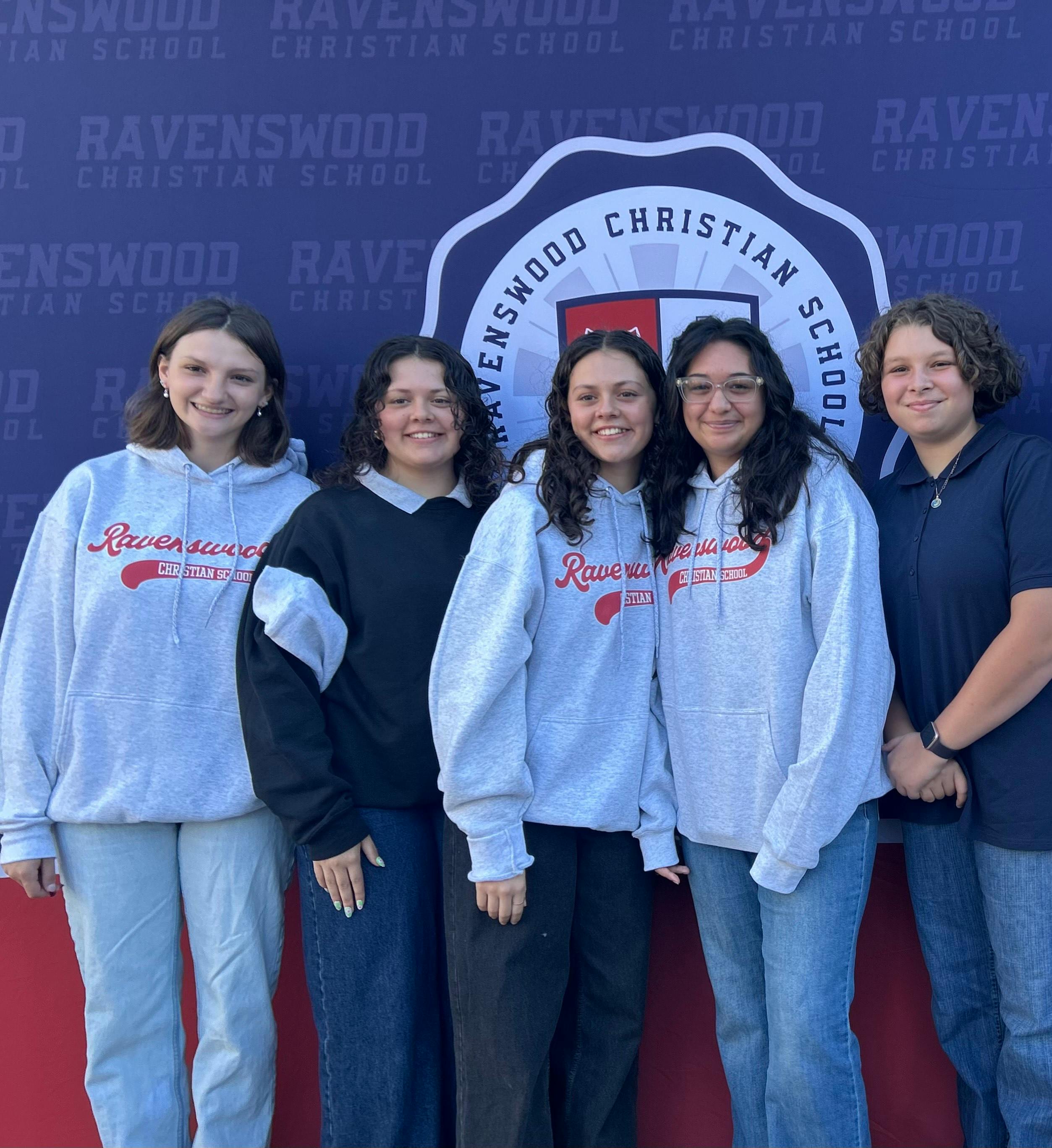 Five people standing in front of a Ravenswood Christian School logo