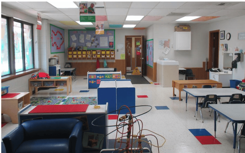 Empty classroom with tables, chairs, and play equipment