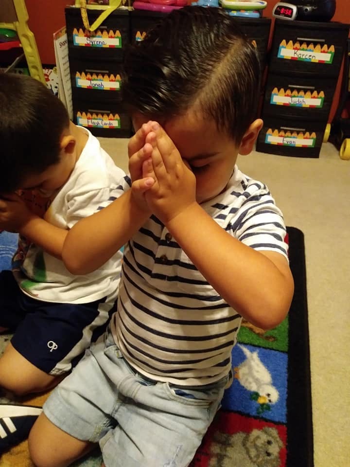 Two children with hands together, eyes closed