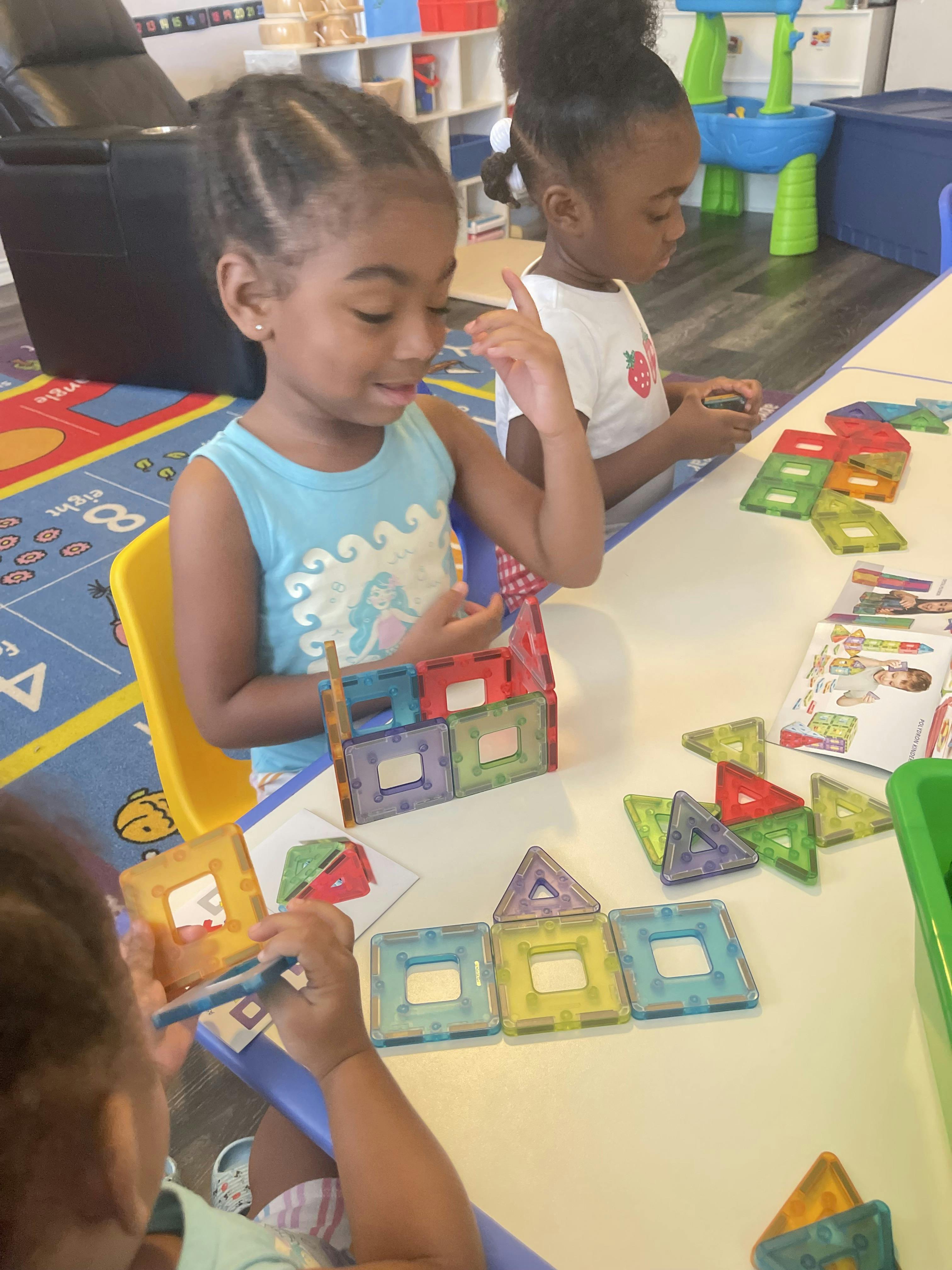 Children building structures with magnetic tiles at a table